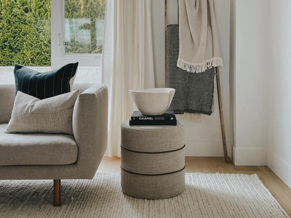 ottoman styled with books and a vase in a living room