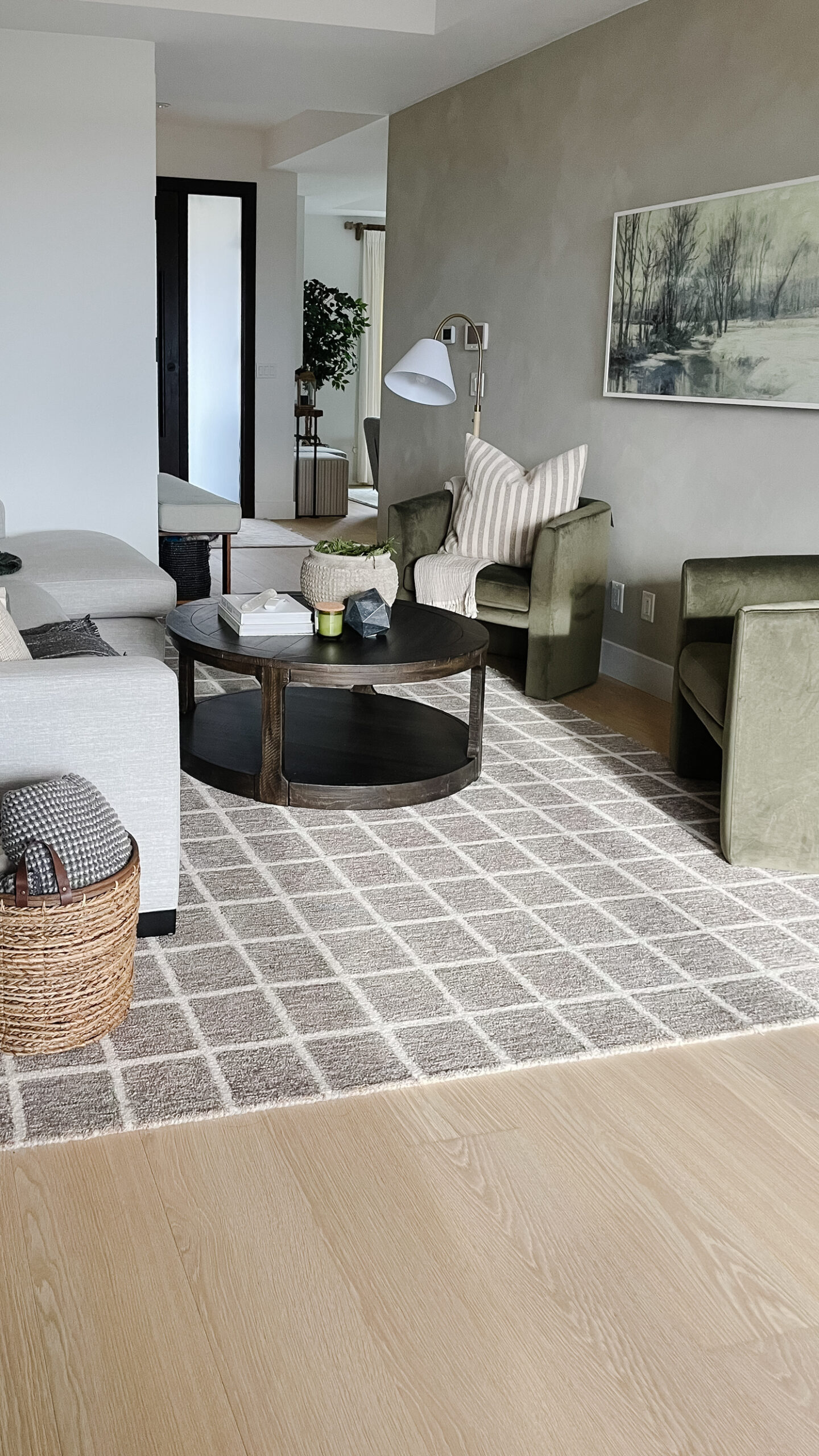 lime wash completed on a wall in the living room. the living room has a sofa that you can barely see, a basket with blankets, a coffee table, two chairs, and a checkered rug.