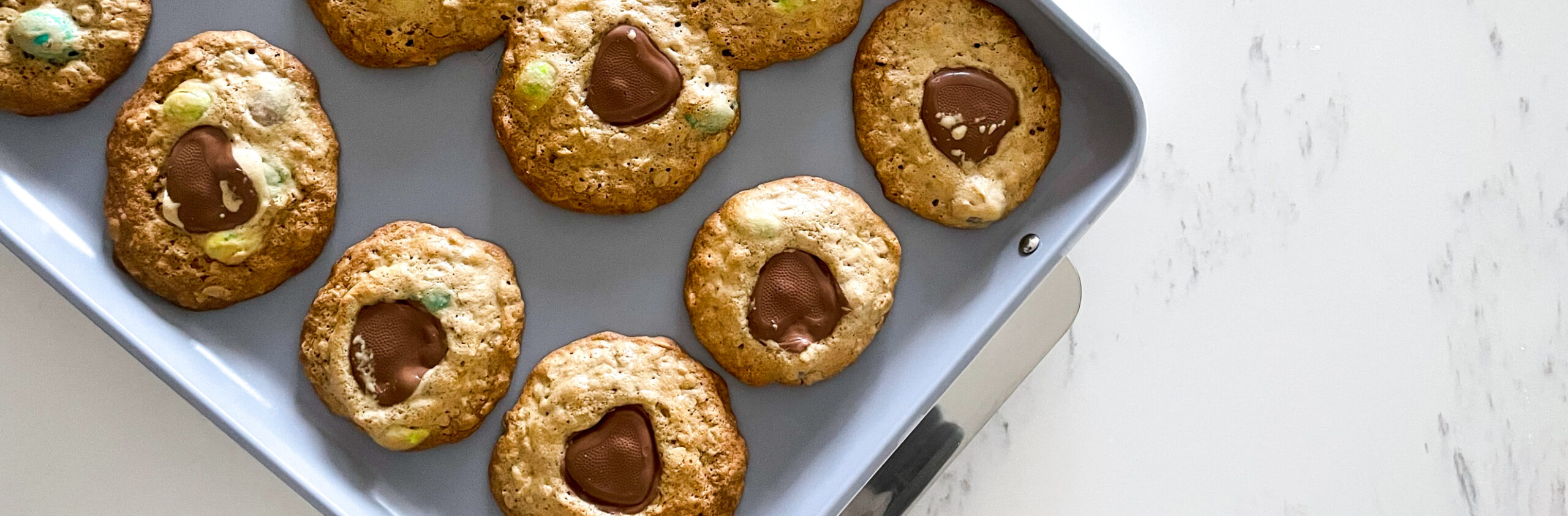 Valentine's Day Monster Cookies with heart chocolates on a baking sheet
