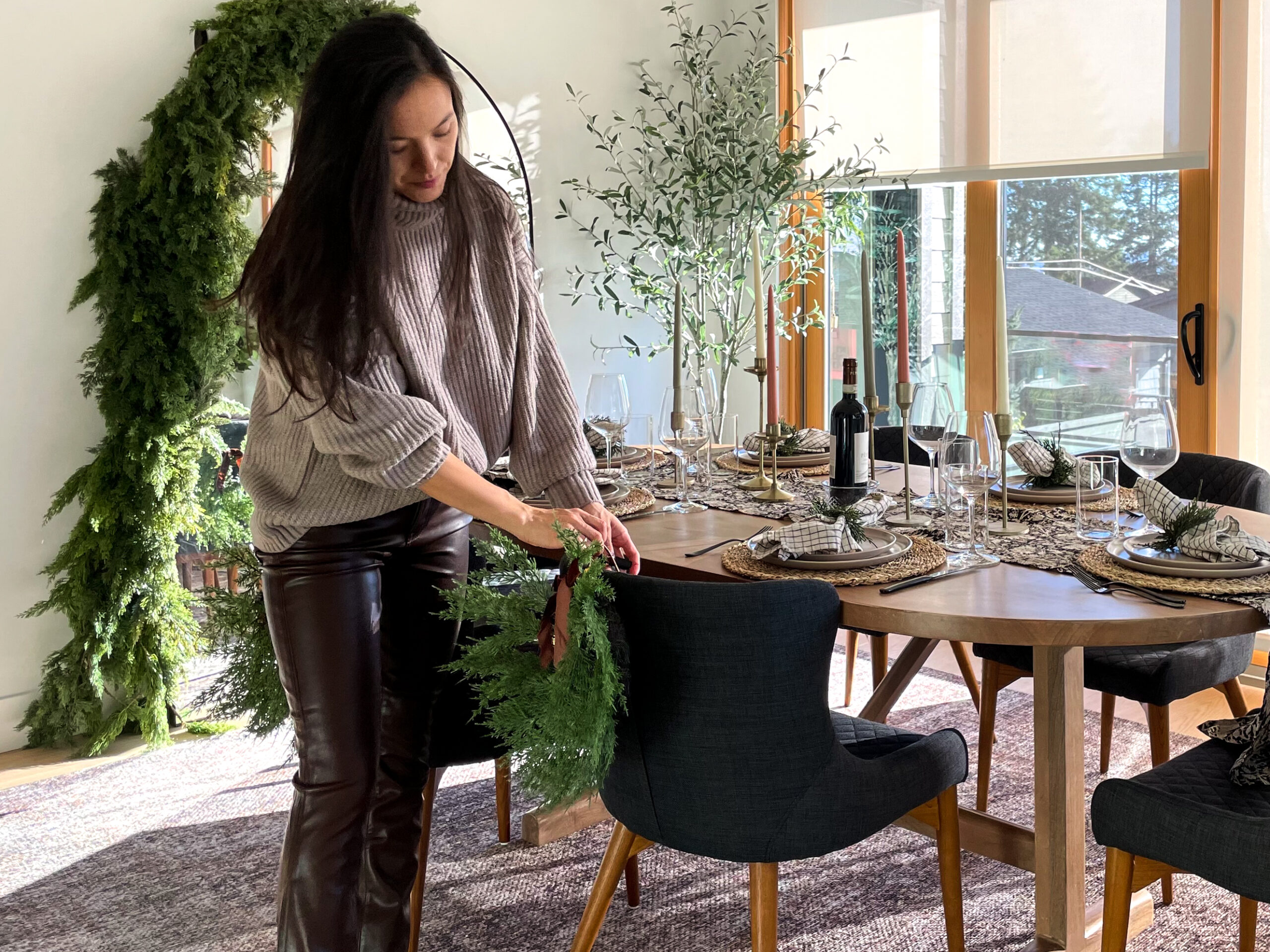 women dressed in holiday outfit setting the table. brown sweater and brown leather pants