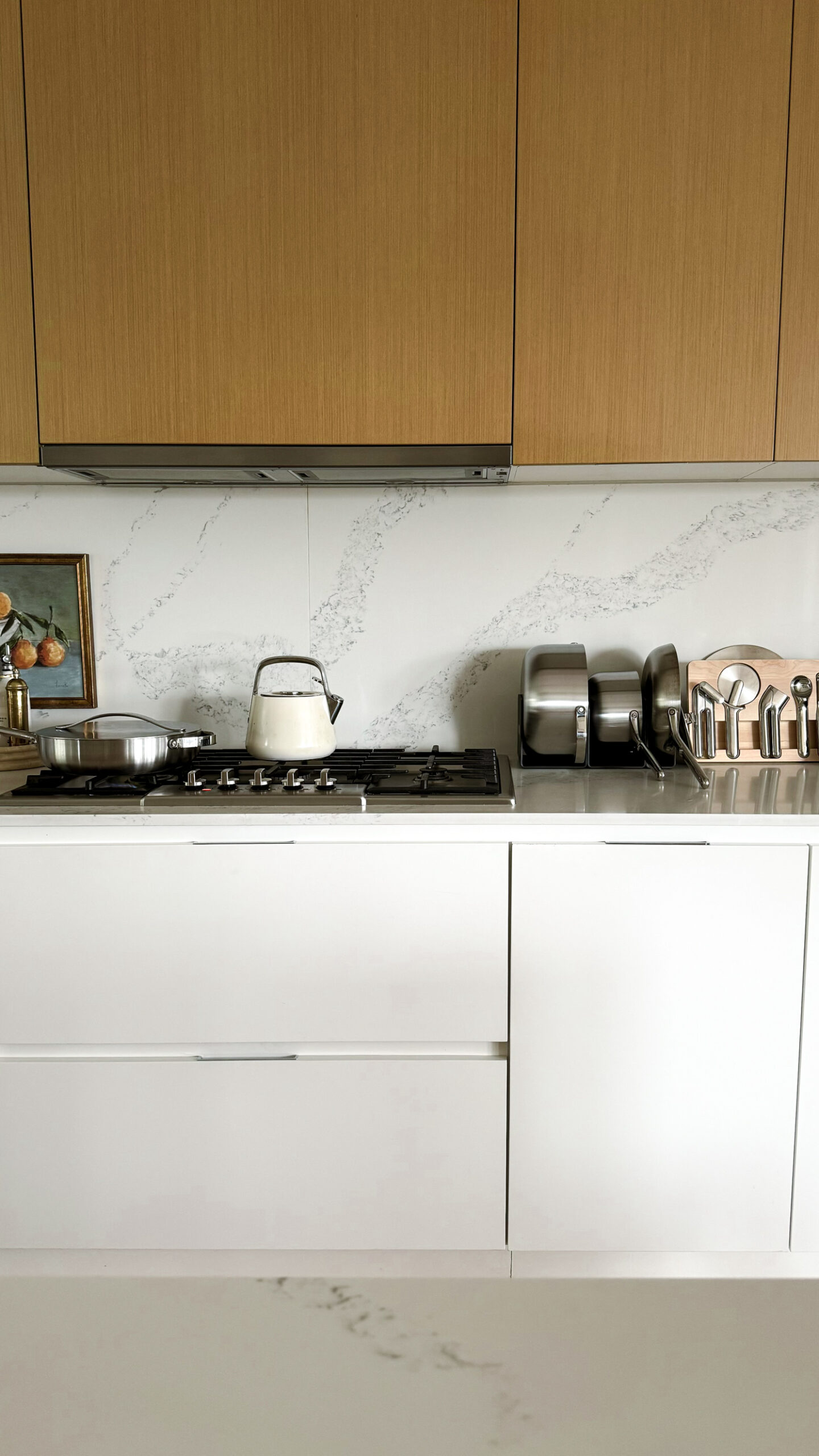 A review of Caraway's stainless steel set that is sitting on a kitchen counter in the magnetic organizers Caraway products come with, plus their new stainless kitchen gadgets sitting on the counter.