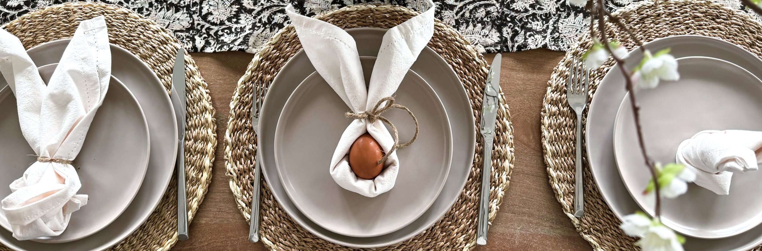 three Easter napkin folds with bunny ears sitting on top of plates