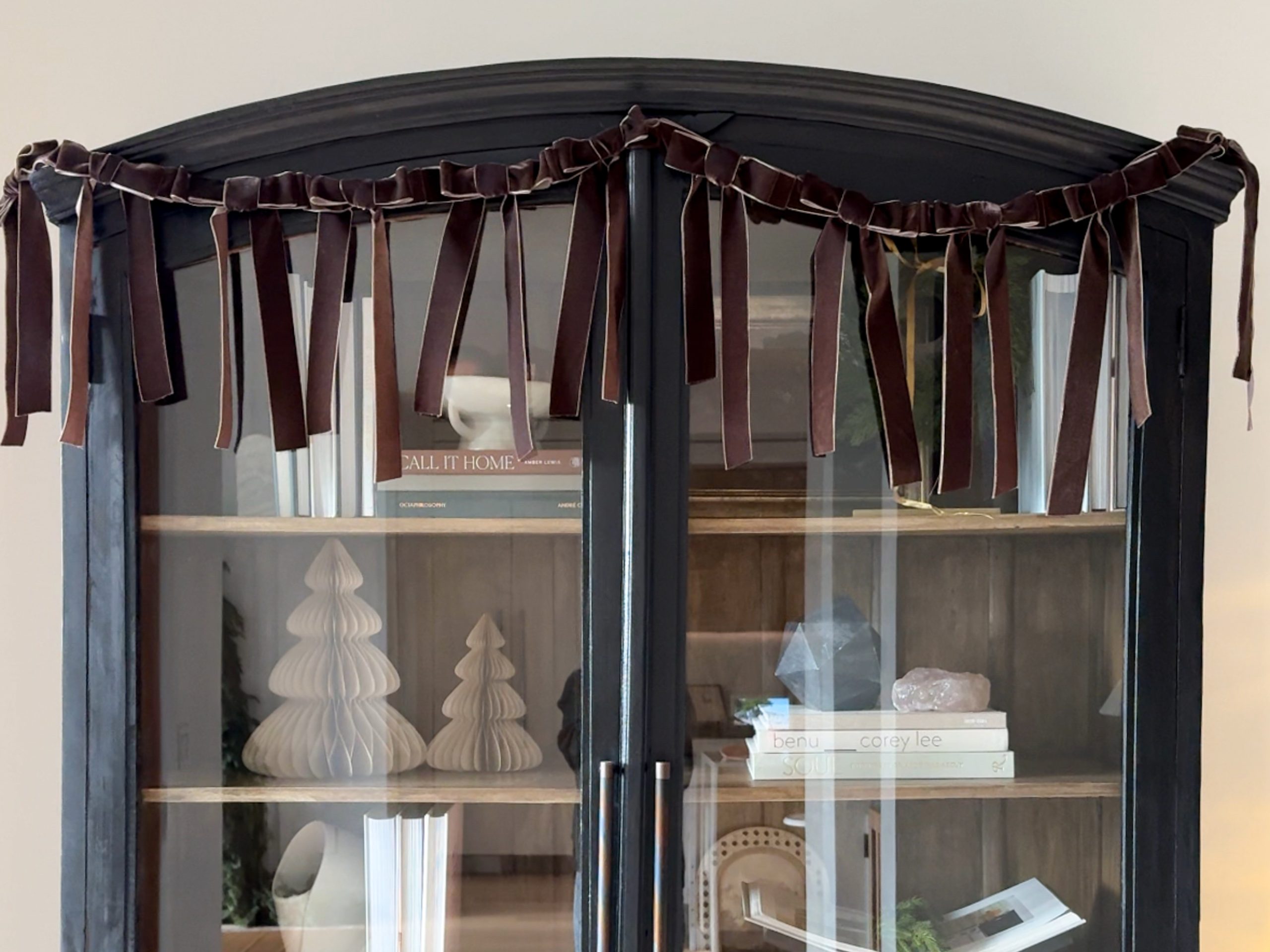 DIY bow garland on top of an arched cabinet