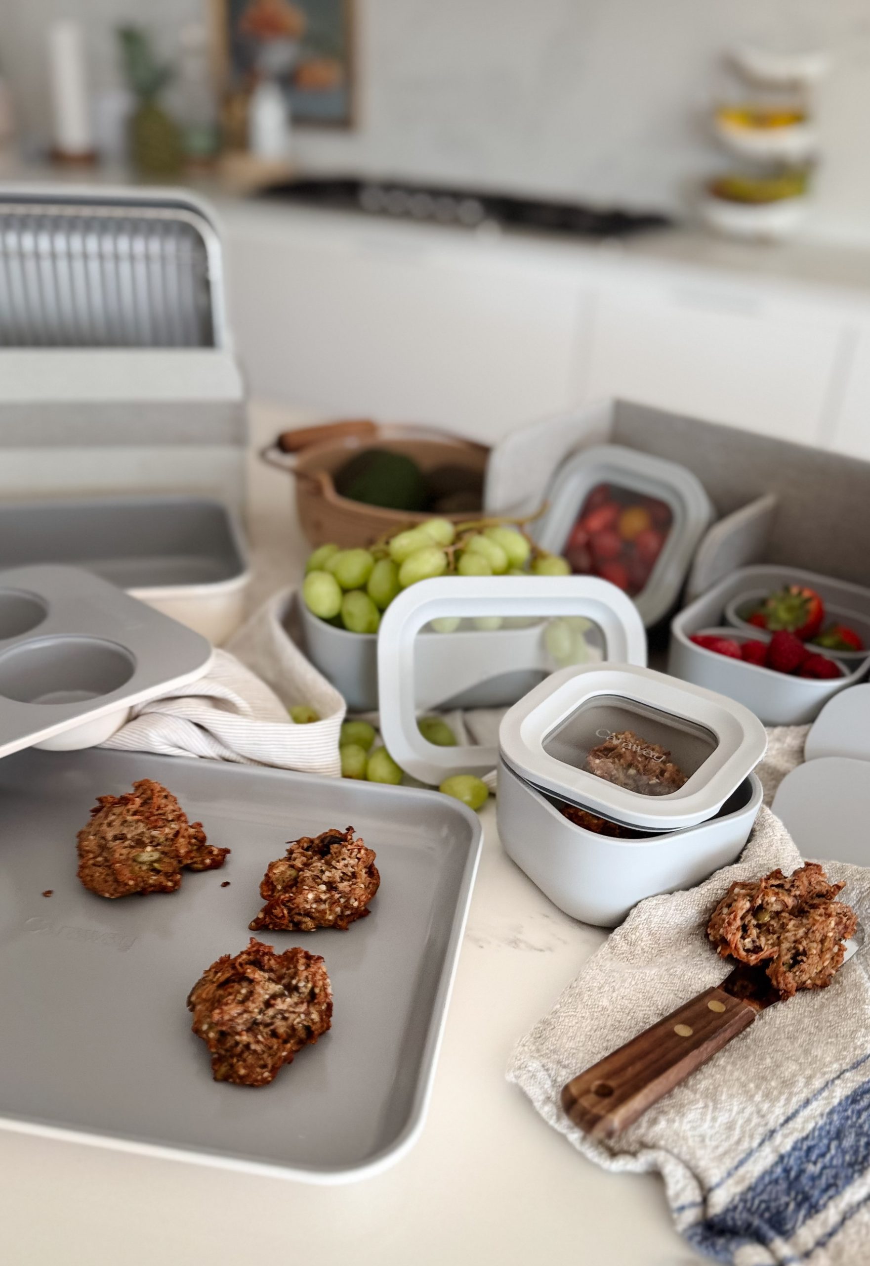 Caraway's mini's picture on the table - their mini storage containers filled with fruits and cookies