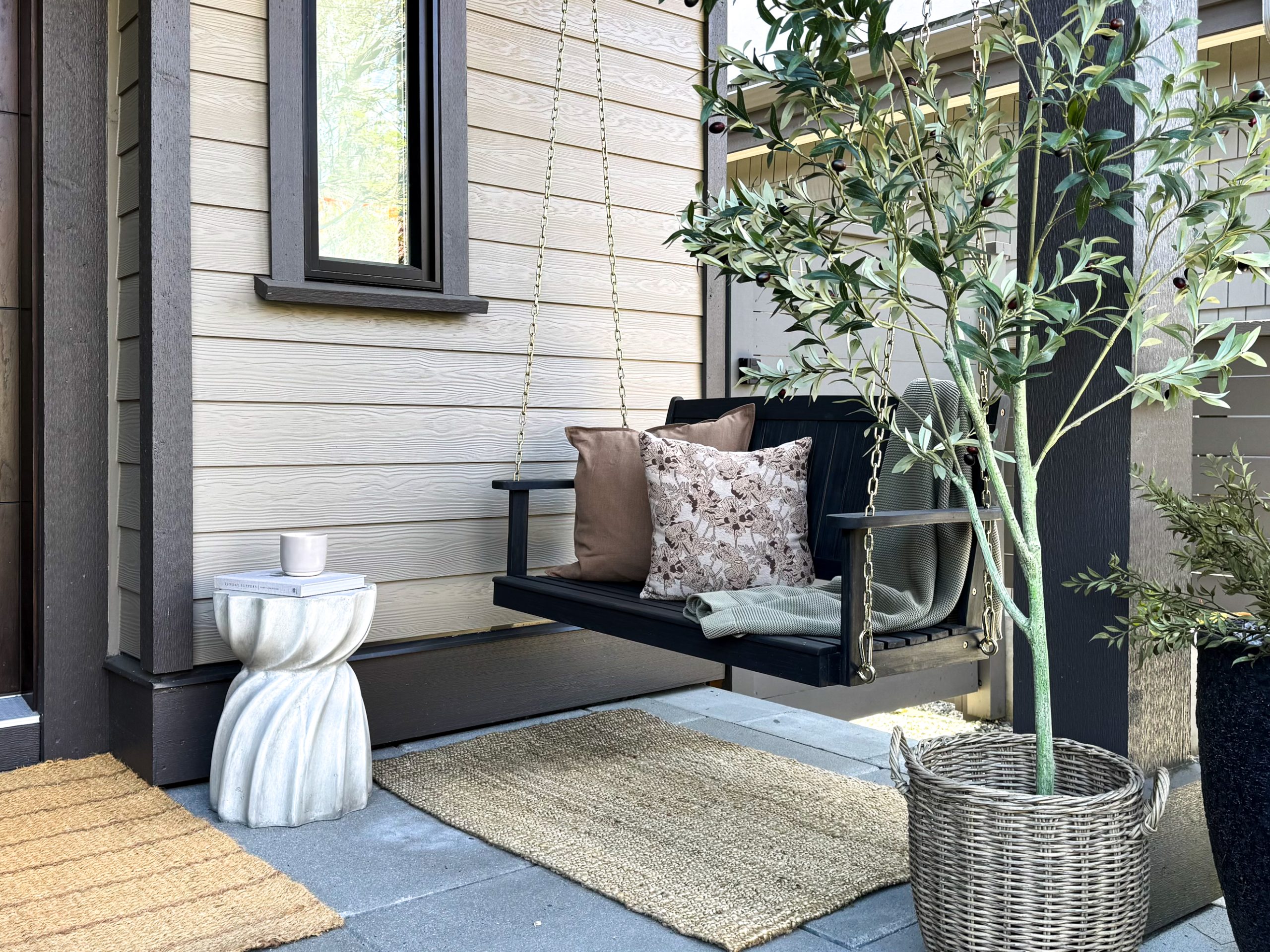 Front proch outdoor oasis styling. With a porch swing, pillows and a throw on the swing and a side table.