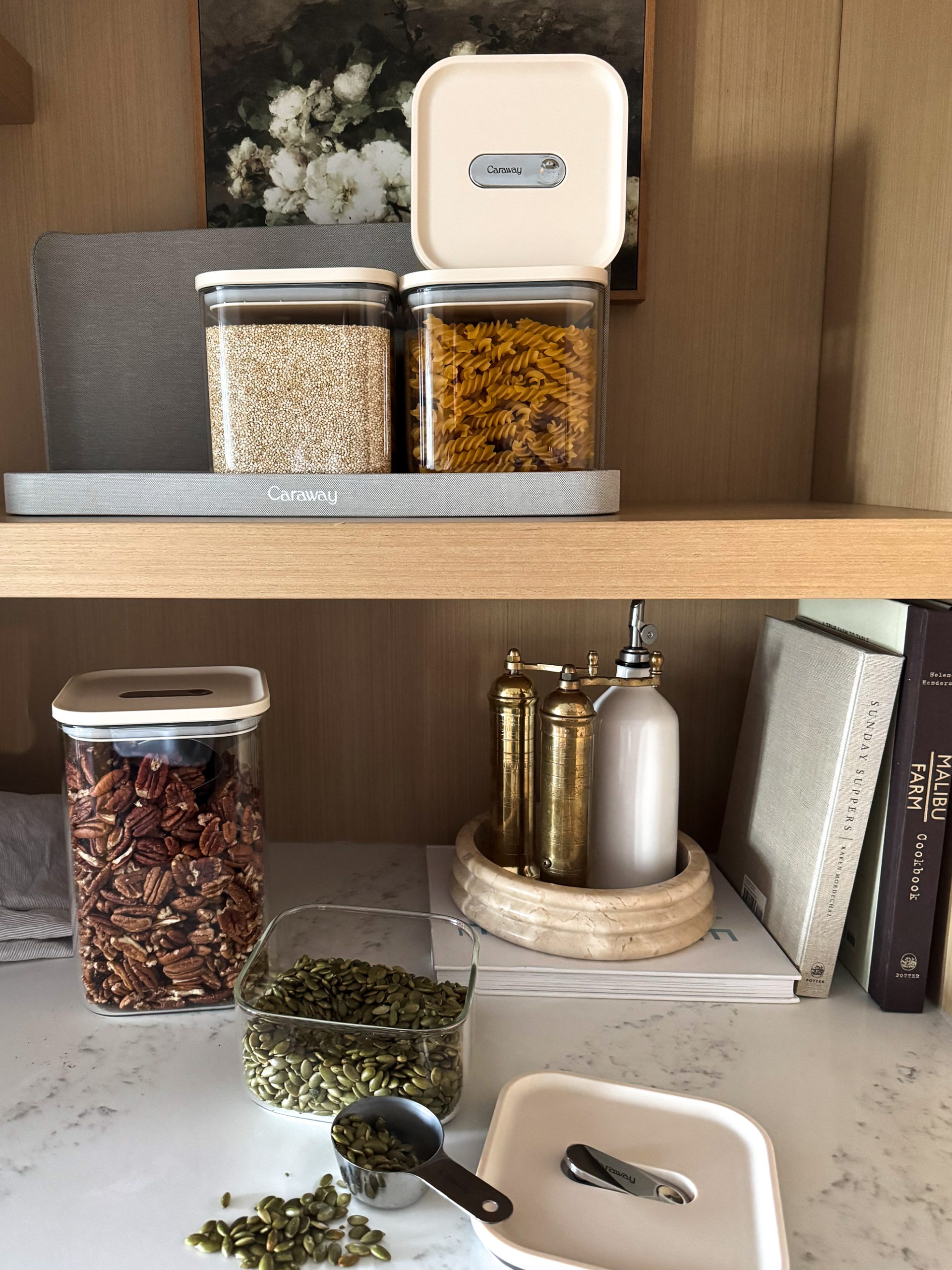 Caraway Glass Airtight Container Set still on a shelf - some filled with pecans, some filled with quinoa, some filled with pasta