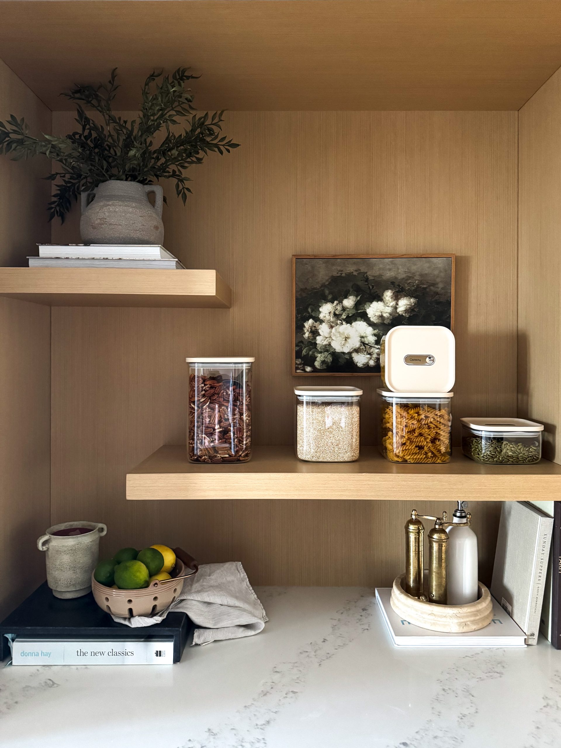 Caraway Glass Airtight Container Set still on a shelf - some filled with pecans, some filled with quinoa, some filled with pasta