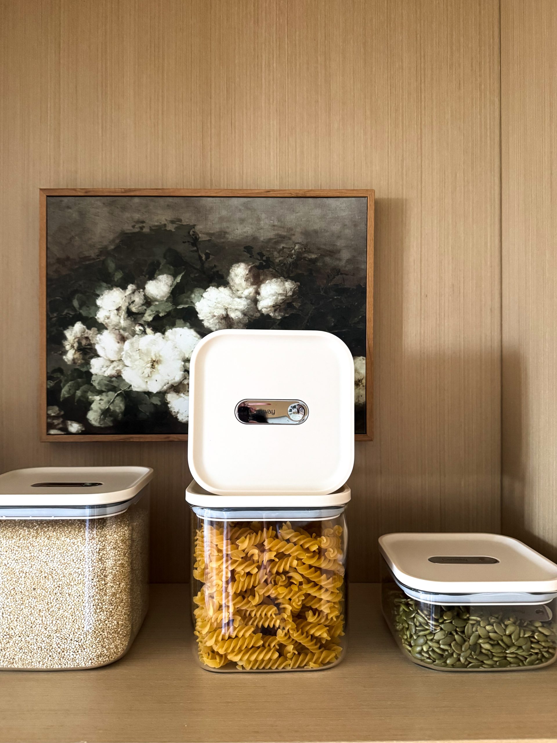 Caraway Glass Airtight Container Set still on a shelf - some filled with pecans, some filled with quinoa, some filled with pasta