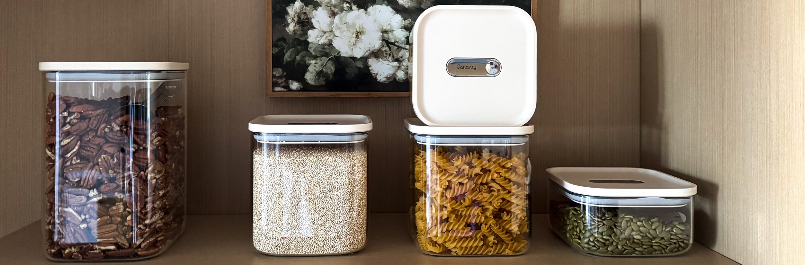 Caraway Glass Airtight Container Set still on a shelf - some filled with pecans, some filled with quinoa, some filled with pasta