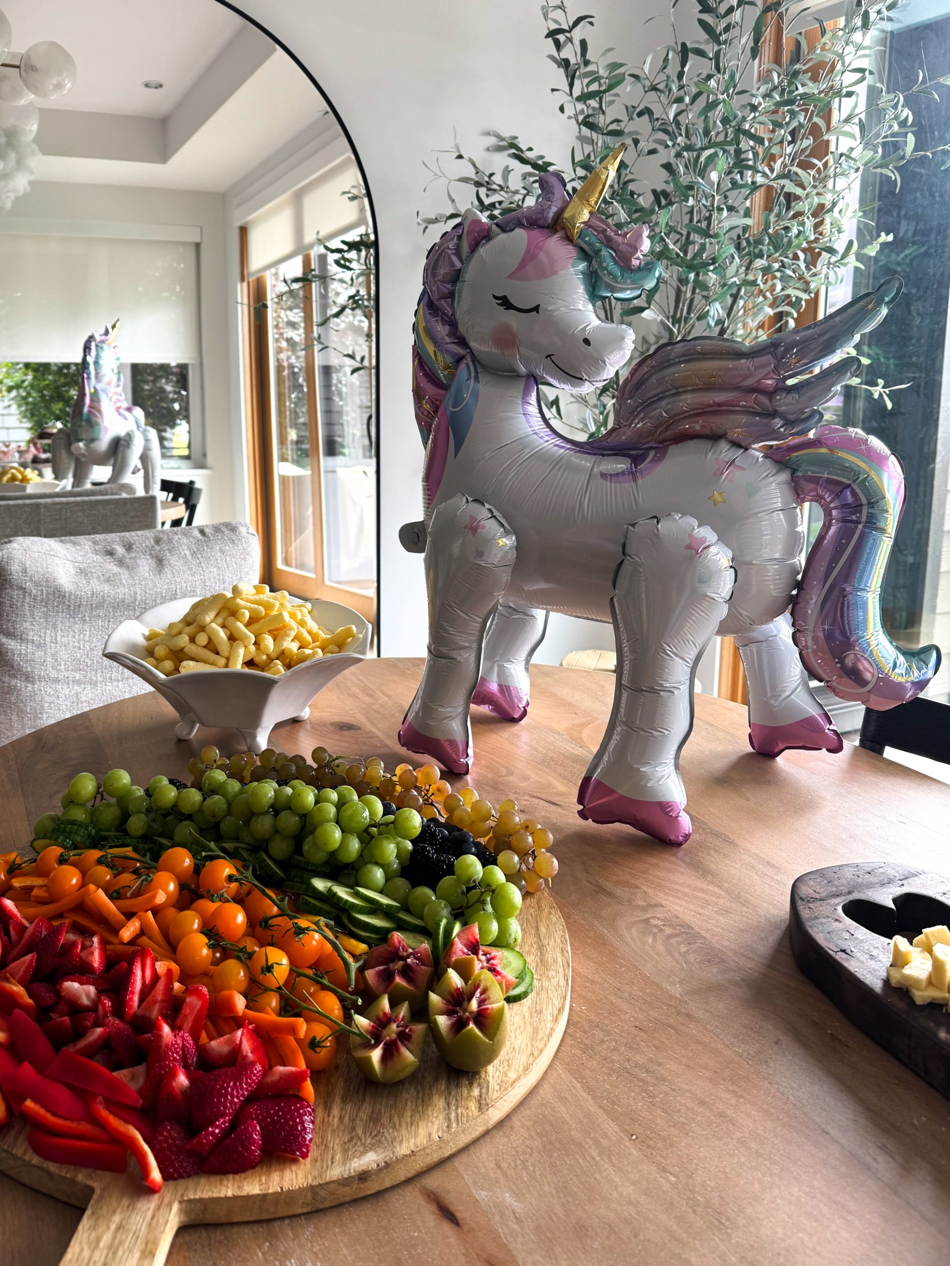 unicorn on top of a dining table with a rainbow fruit and veggie board