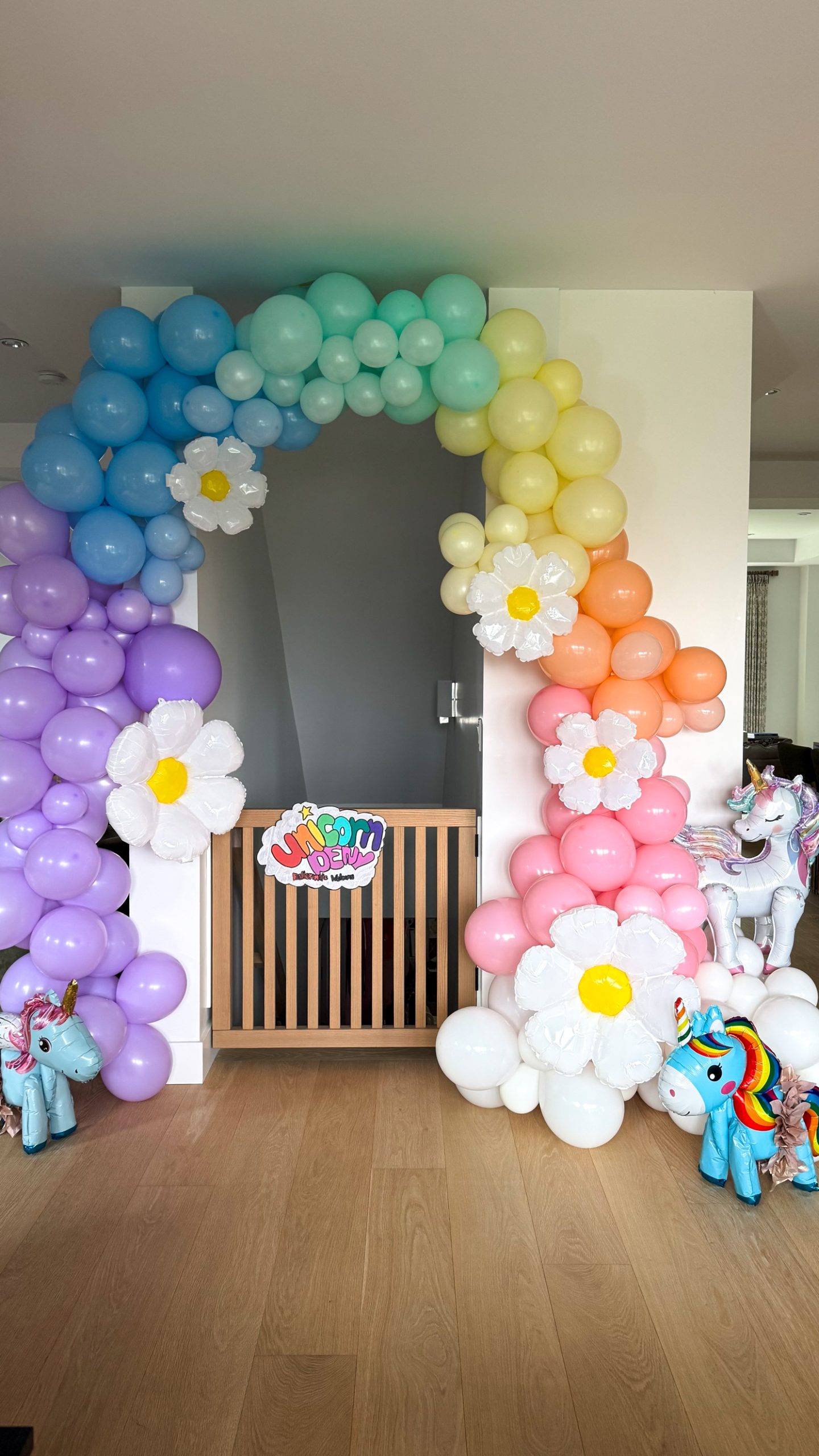 unicorn ballerina birthday party with a rainbow balloon arch, a few daisy's and some unicorns with tutu's on them leading into the "unicorn den"
