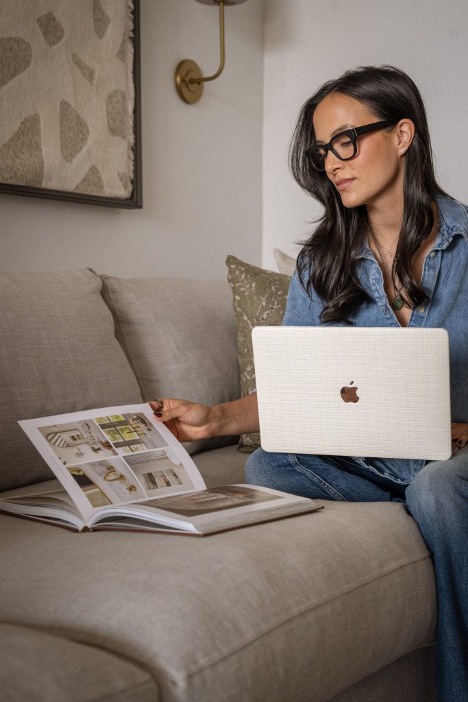 Samantha Potter Home flipping through a book and on her computer while sitting on a couch